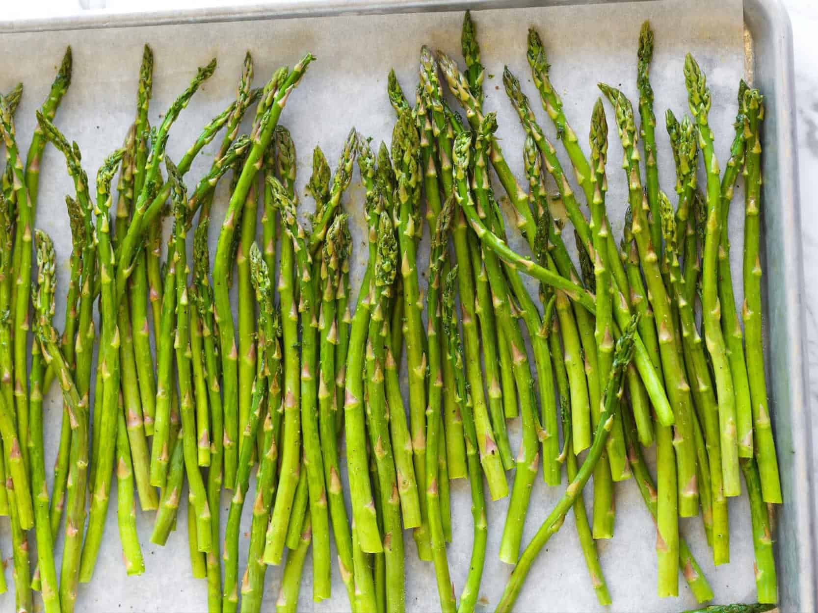 Seasoned asparagus on a baking sheet ready for the oven
