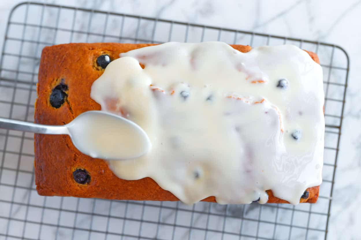 Spreading the yogurt icing over the baked and cooled blueberry bread