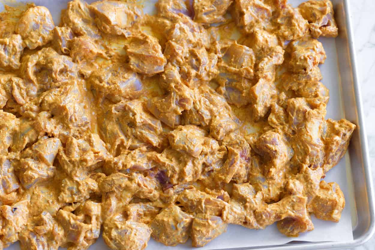 Roasting yogurt-marinated chicken on a baking sheet for butter chicken
