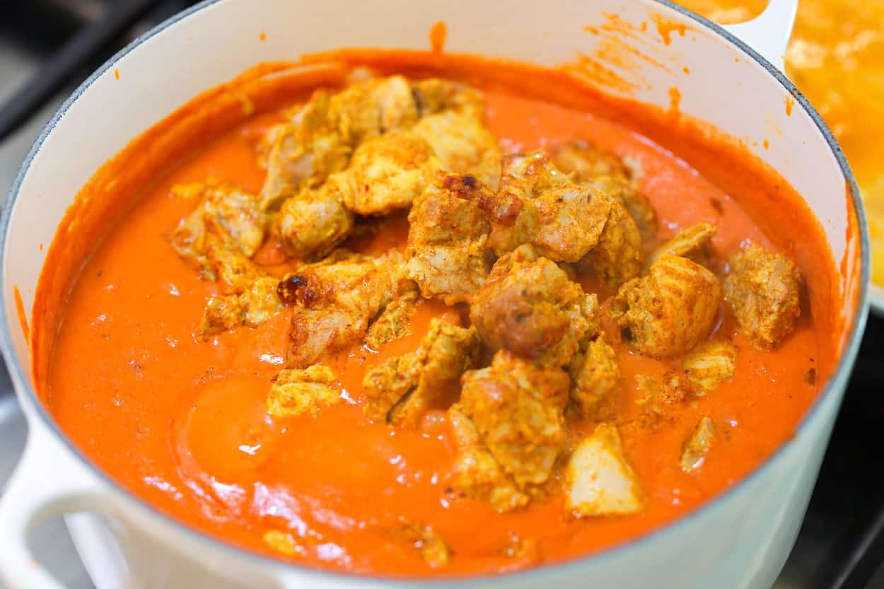 Stirring the roasted marinated chicken into the butter chicken curry
