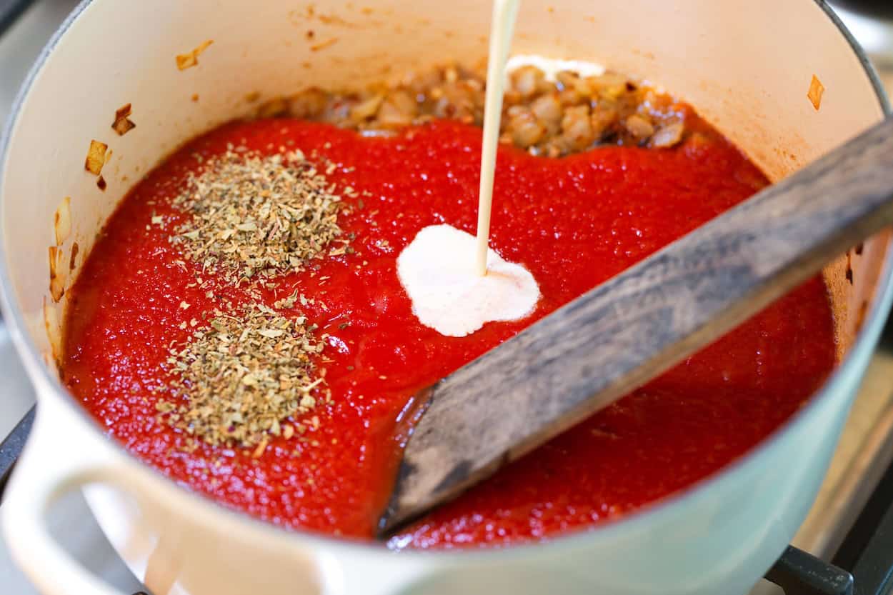 Adding tomato sauce, cream, and basil for the butter chicken curry sauce