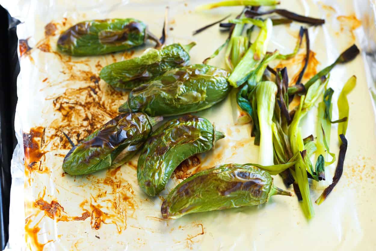 Broiled jalapeños and green onions on a baking sheet
