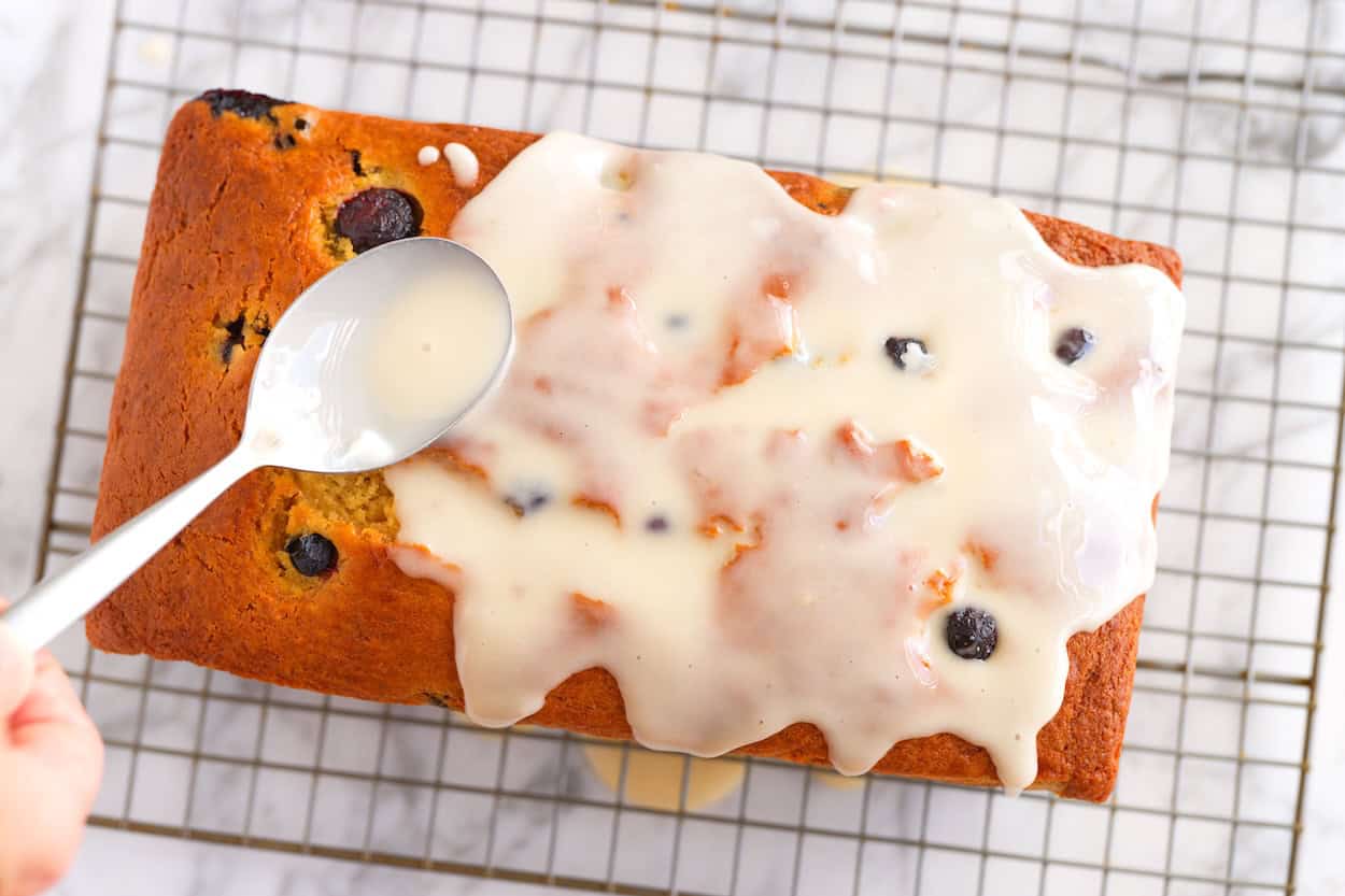 Spreading lemon icing over the blueberry bread