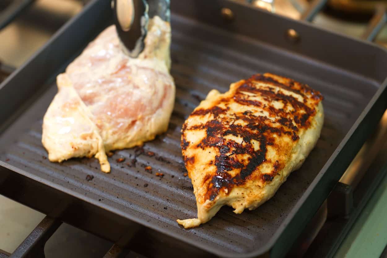 Grilling the chicken in a grill pan before baking in the oven.