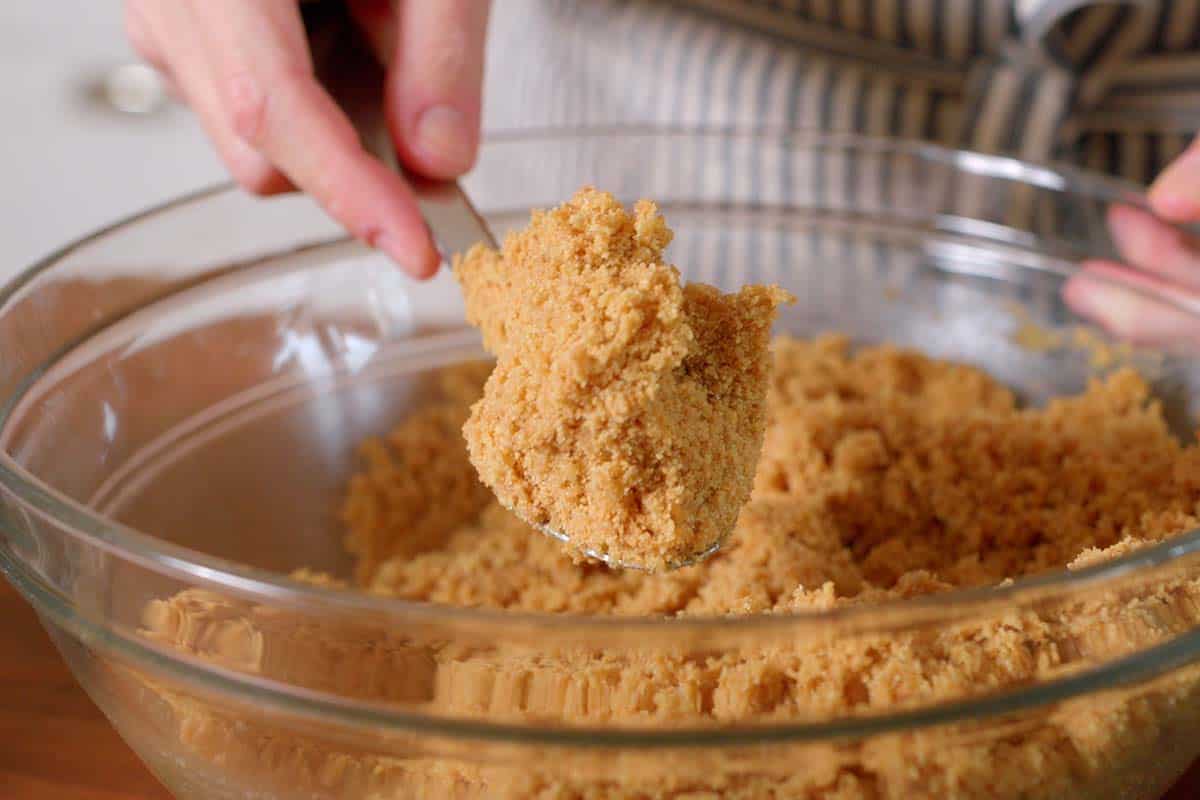 Graham cracker crust mixture that looks like sand ready to be packed into the cheesecake pan