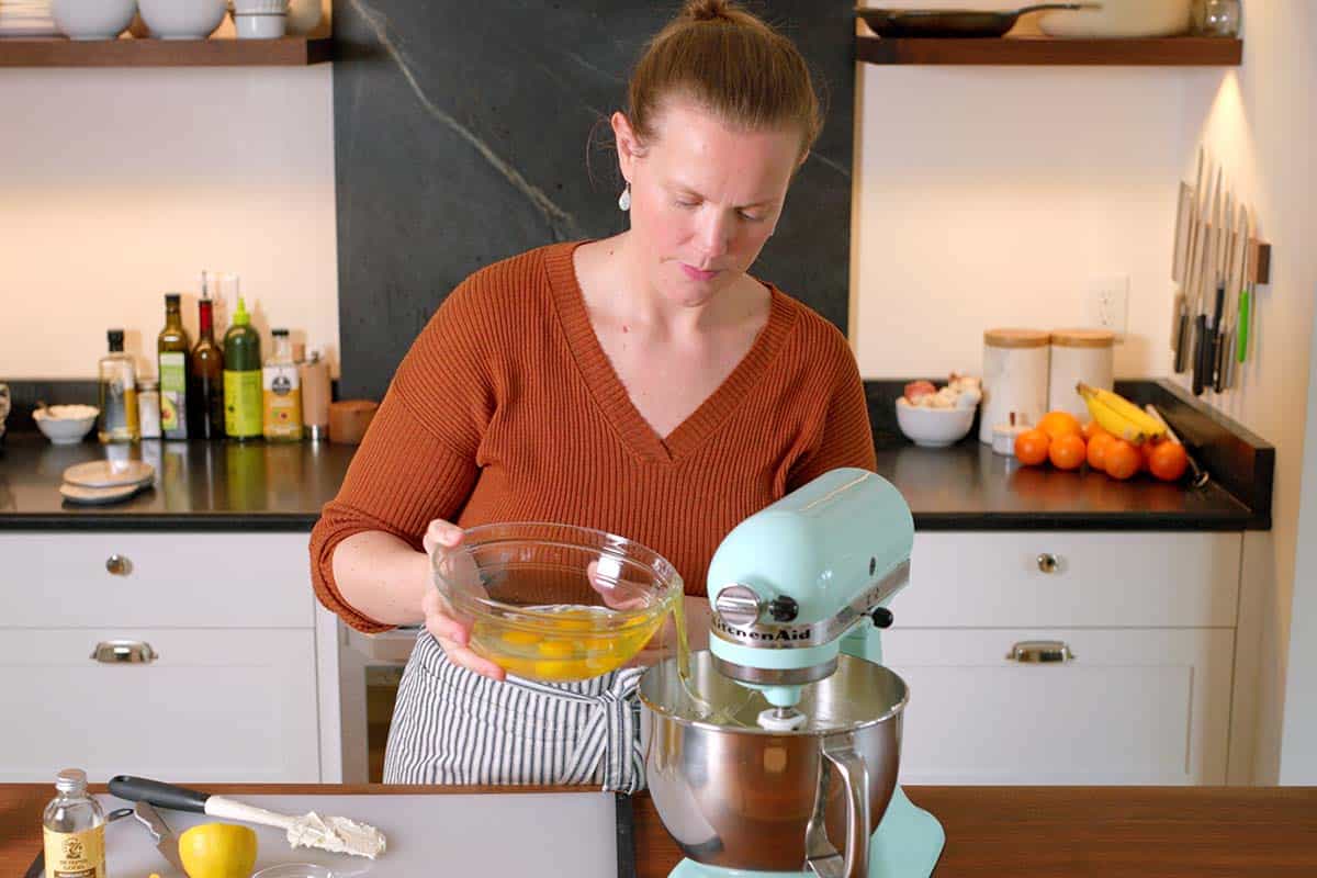 Adding the eggs slowly to a stand mixer for the cheesecake filling