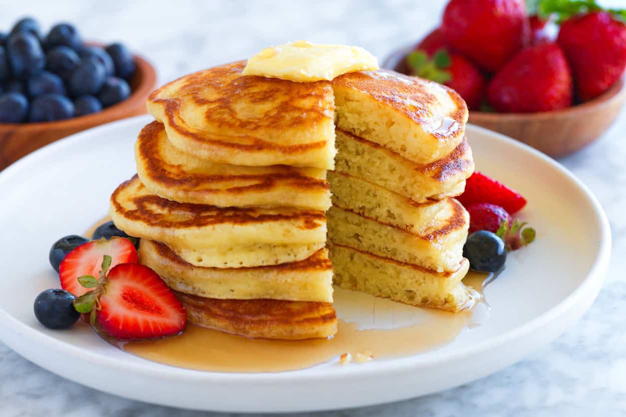 A stack of pancakes with a wedge cut out to show how fluffy they are in the middle.