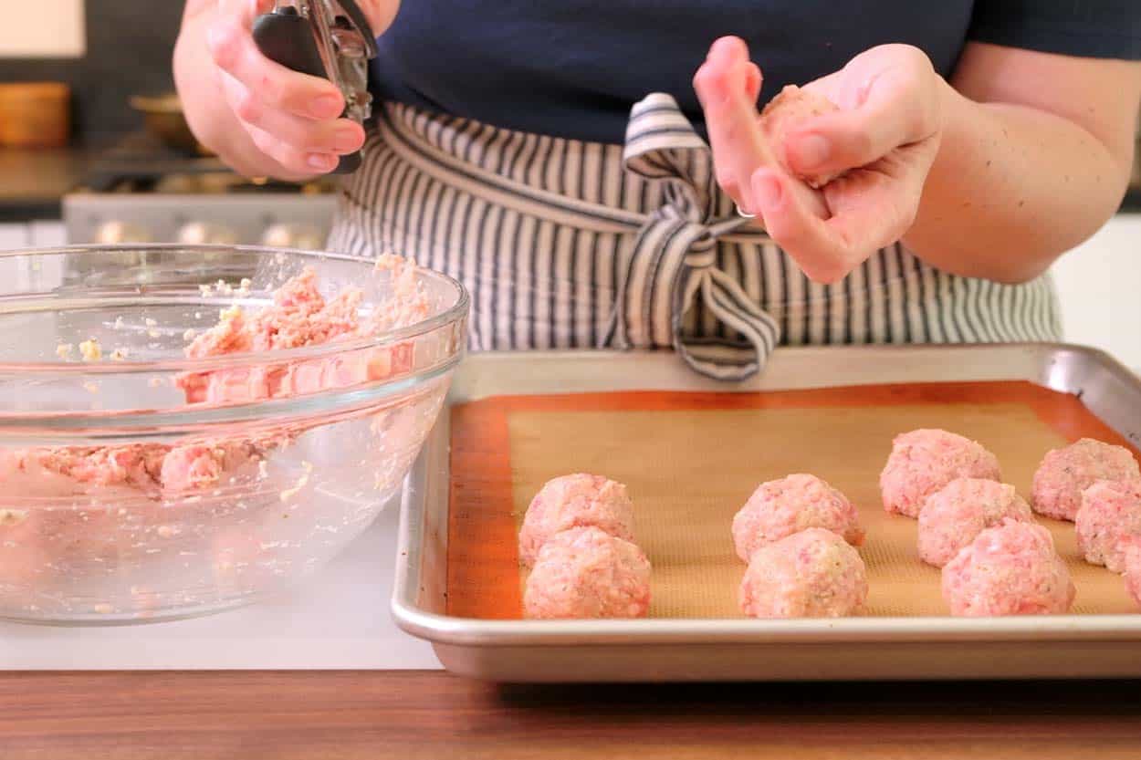 Rolling meatballs and placing onto a baking sheet ready to bake