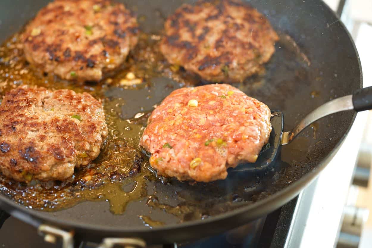 Cooking pork burger patties in a skillet